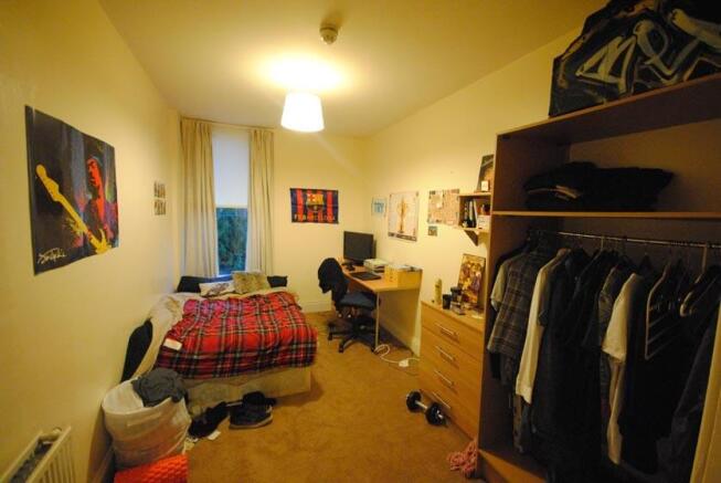 A well-lit bedroom featuring a single bed, a st...