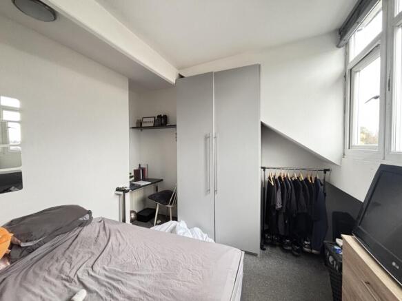 A bright, tidy bedroom featuring a comfortable ...