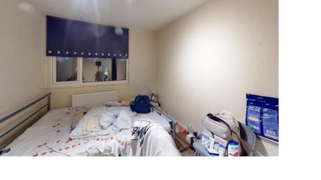 A modest single bedroom with a bed, a small des...