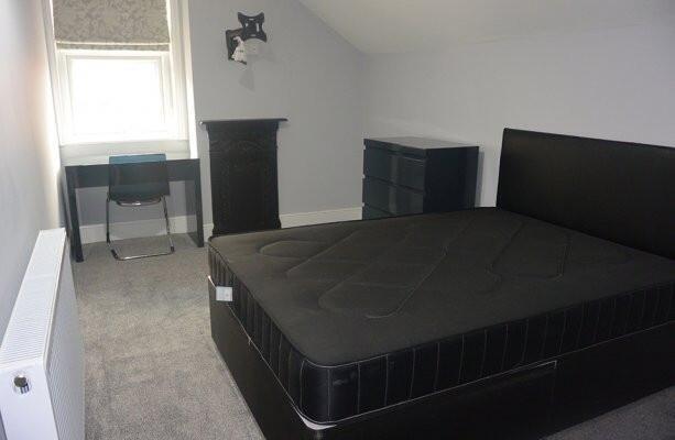 A spacious master bedroom featuring a large bed...