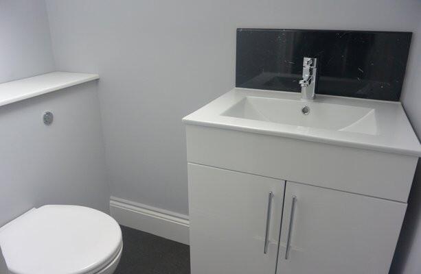 A modern, clean bathroom featuring a white sink...