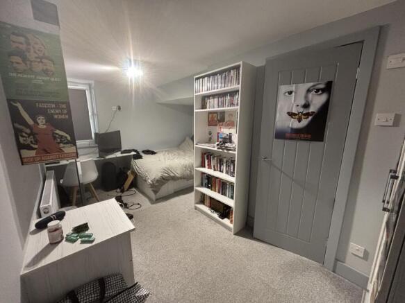 A cozy bedroom featuring a bed, a bookshelf, an...