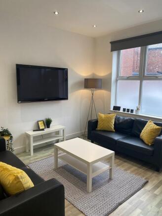 Bright, modern living room with two black leath...