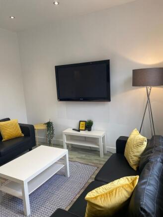 Bright modern living room with wall-mounted TV,...