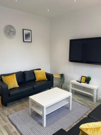 Bright, modern living room with black sofas, co...