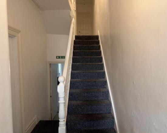 Carpeted staircase with a painted wooden balust...