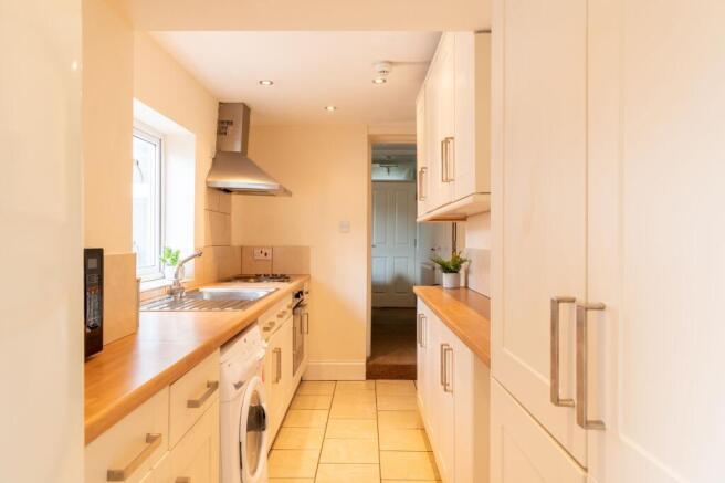 Bright, modern galley kitchen with wooden count...