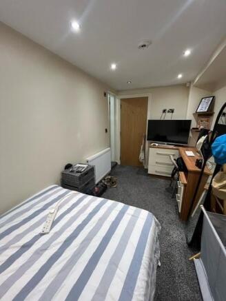 A cozy bedroom with a neatly made bed featuring...