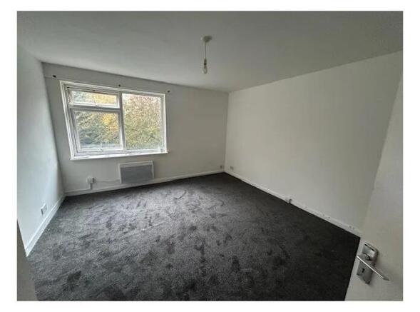 Bright, neutrally decorated bedroom with a larg...