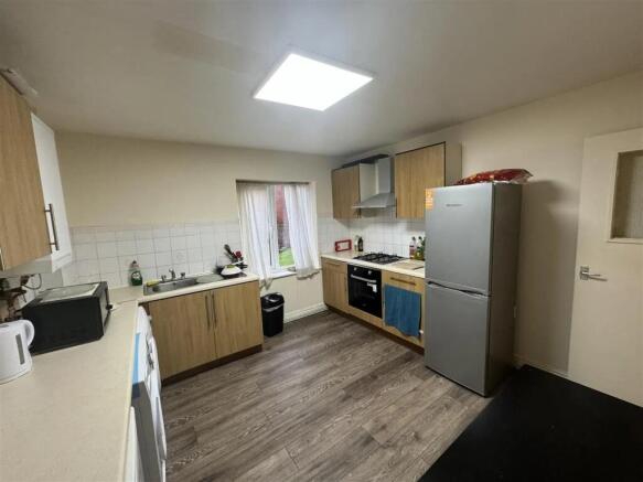Well-lit kitchen featuring wooden cabinets, a m...