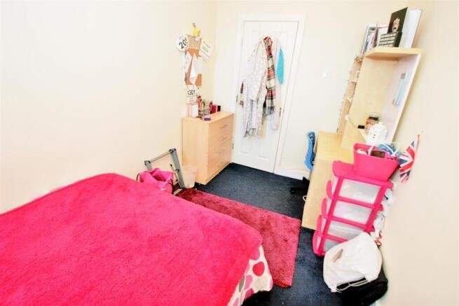 A cozy student bedroom featuring a vibrant pink...