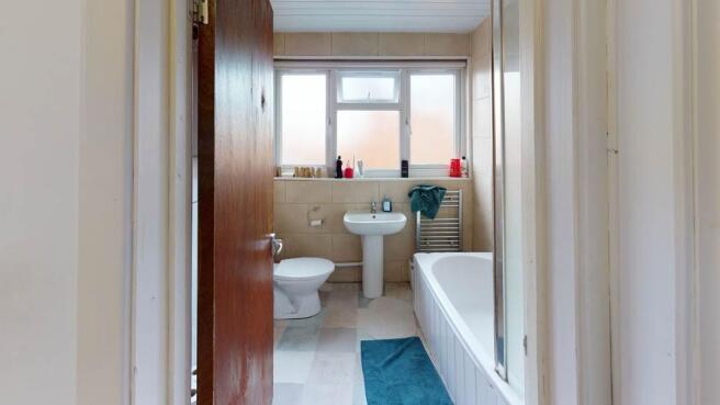 A clean, well-lit bathroom featuring a bathtub,...