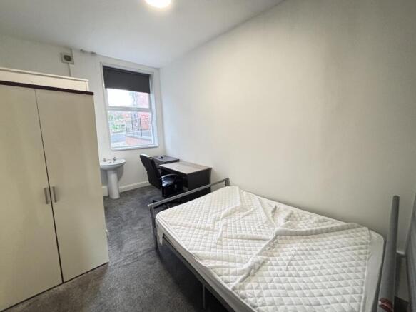 A tidy and well-lit student bedroom featuring a...