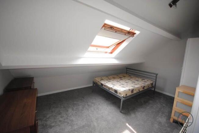 A neatly maintained bedroom with a large skylig...