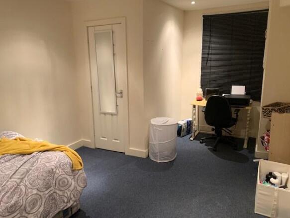 A tidy bedroom featuring a bed, a desk with a c...