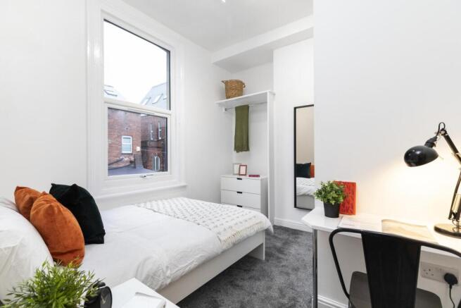 A bright and cozy student bedroom featuring a c...