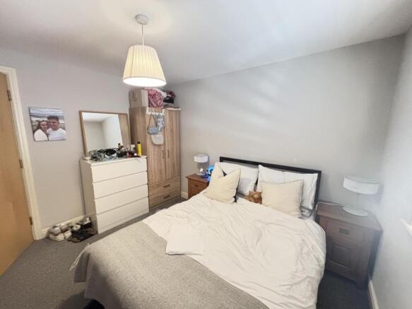 A spacious, well-lit master bedroom with a comf...