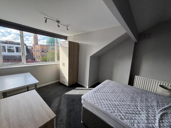 A well-lit, clean bedroom featuring a double be...