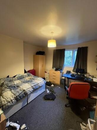 A modest student bedroom featuring a bed, desk ...