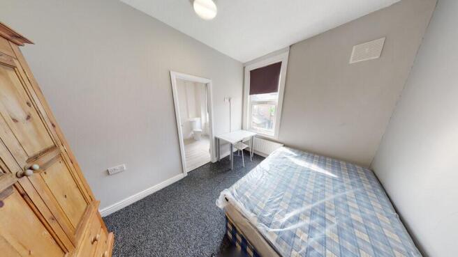 A cozy single bedroom featuring a bed with a fi...