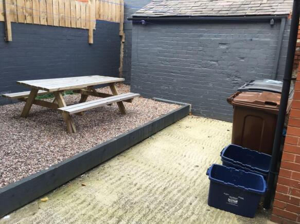 Private rear paved courtyard with raised gravel...