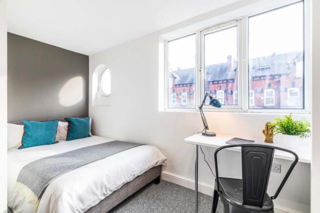 Bright, neatly styled double bedroom with a com...