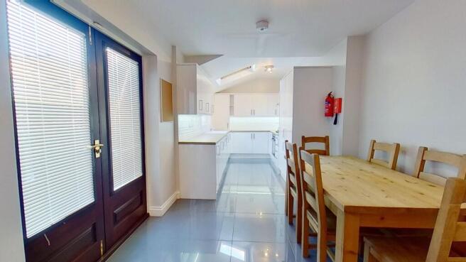 Bright modern galley kitchen and dining area wi...