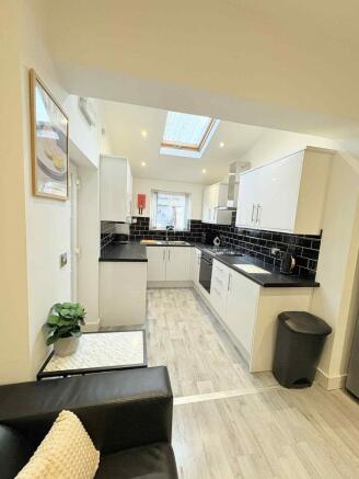 Bright modern kitchen with white cabinets, blac...