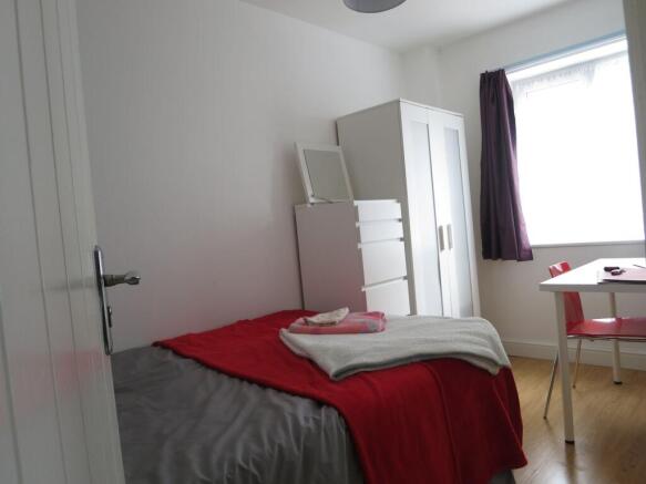 Bright, simply furnished bedroom with a double ...
