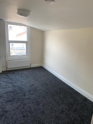 A well-lit room with a clean carpet and a windo...