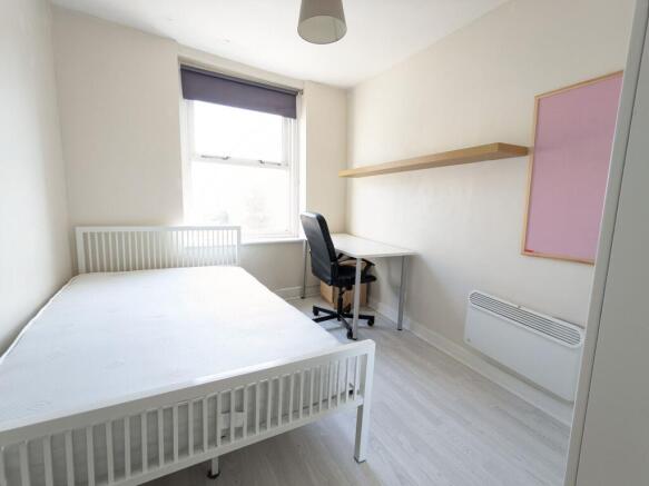 Bright, simply furnished bedroom with a white b...