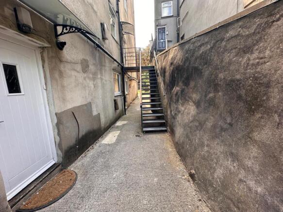 Narrow exterior alleyway with a secure white en...