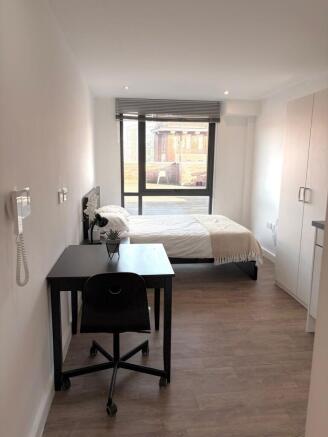 Bright, modern single bedroom with a large wind...