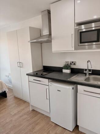 Modern compact kitchen with white cabinets, bla...