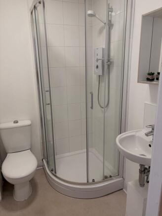 Bright, modern bathroom with a curved glass sho...