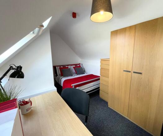 Bright, neatly furnished bedroom with a comfort...