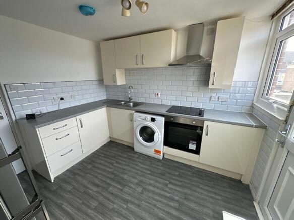 A modern kitchen featuring sleek cream cabinets...