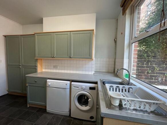 Bright, tidy kitchen with sage-green fitted cup...