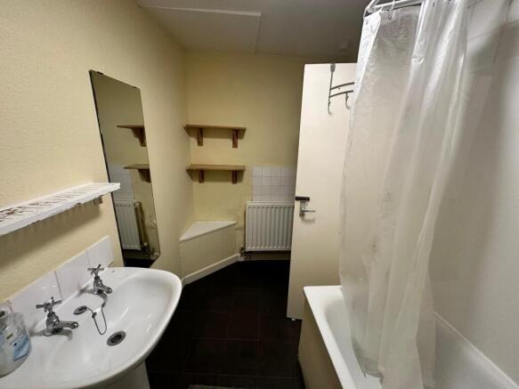 Compact bathroom with a white basin and bathtub...