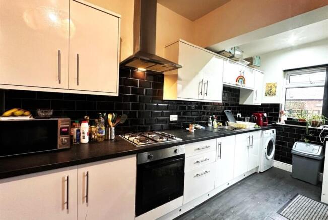 Bright modern kitchen with white cabinetry, bla...
