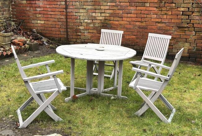 Private walled garden with a round wooden table...