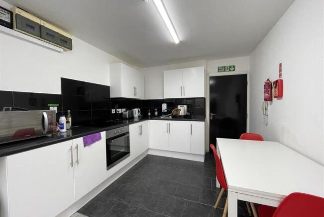 Modern communal kitchen with sleek white cabine...