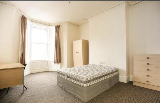 Bright, airy bedroom with a large bay window, n...