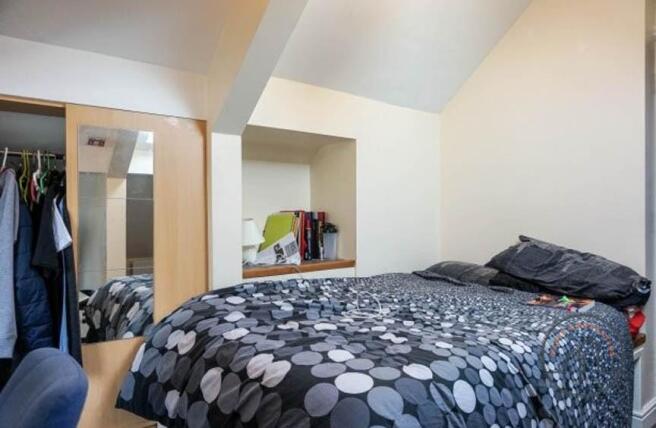 A cozy bedroom featuring a bed with a patterned...