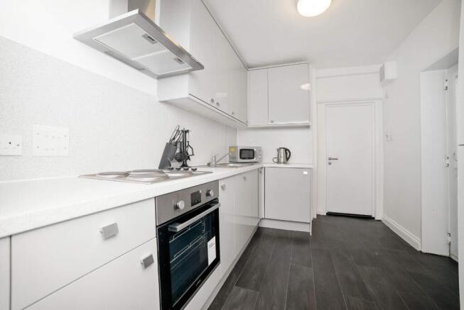 Bright modern galley kitchen with integrated ov...