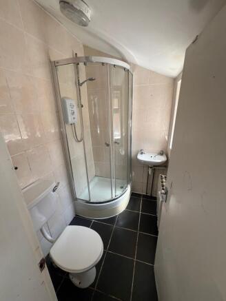 Compact bathroom featuring a modern curved glas...