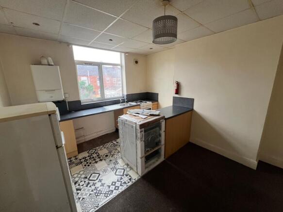 A compact kitchen space with patterned tiled fl...