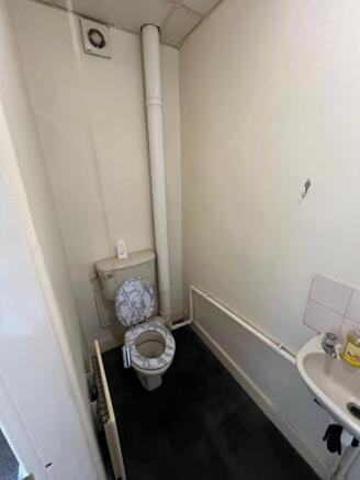 Compact toilet room featuring a white toilet wi...