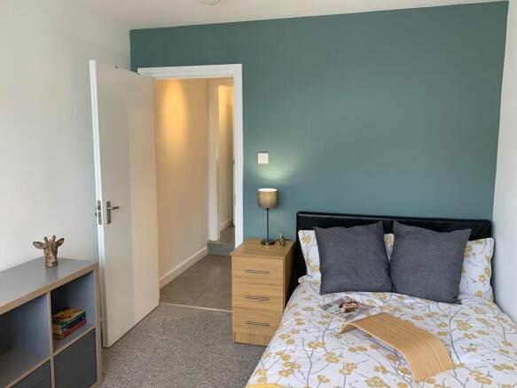 Bright, neatly arranged single bedroom with a f...