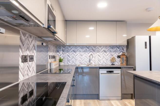 Bright, modern kitchen with glossy cabinets, in...